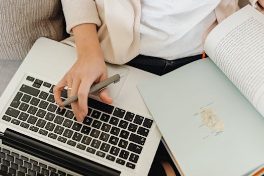Close-up of a person working on a laptop and reading a free food safety-related book